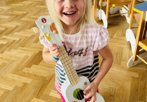 Dziewczynka trzyma gitarę.