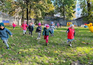 Dzieci biegają po ogrodzie przedszkolnym.