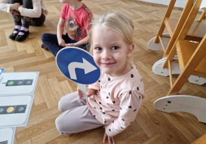 Dziecko trzyma znak drogowy.