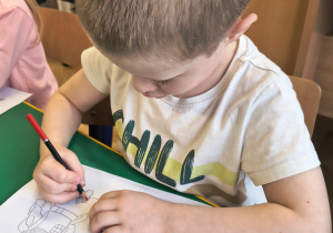 Chłopiec ozdabia list.