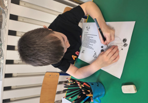 Chłopiec ozdabia list.